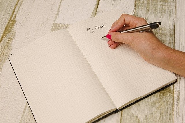 Pessoa anotando planos em caderno