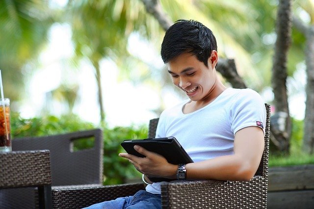 Homem sorrindo enquanto usa tablet