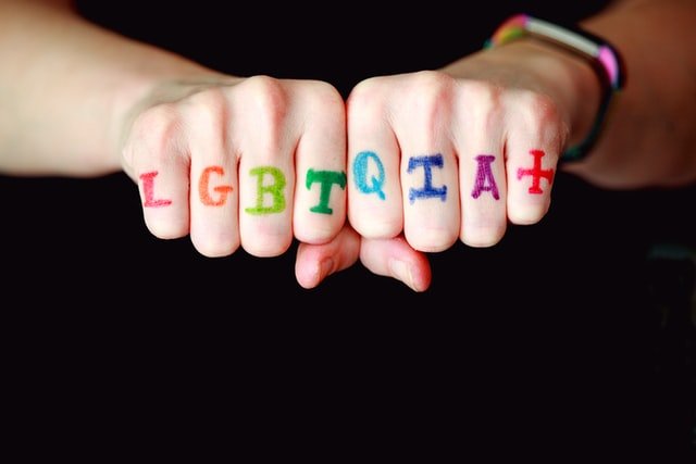 Mãos com as letras LGBTQIA+ escritas nos dedos