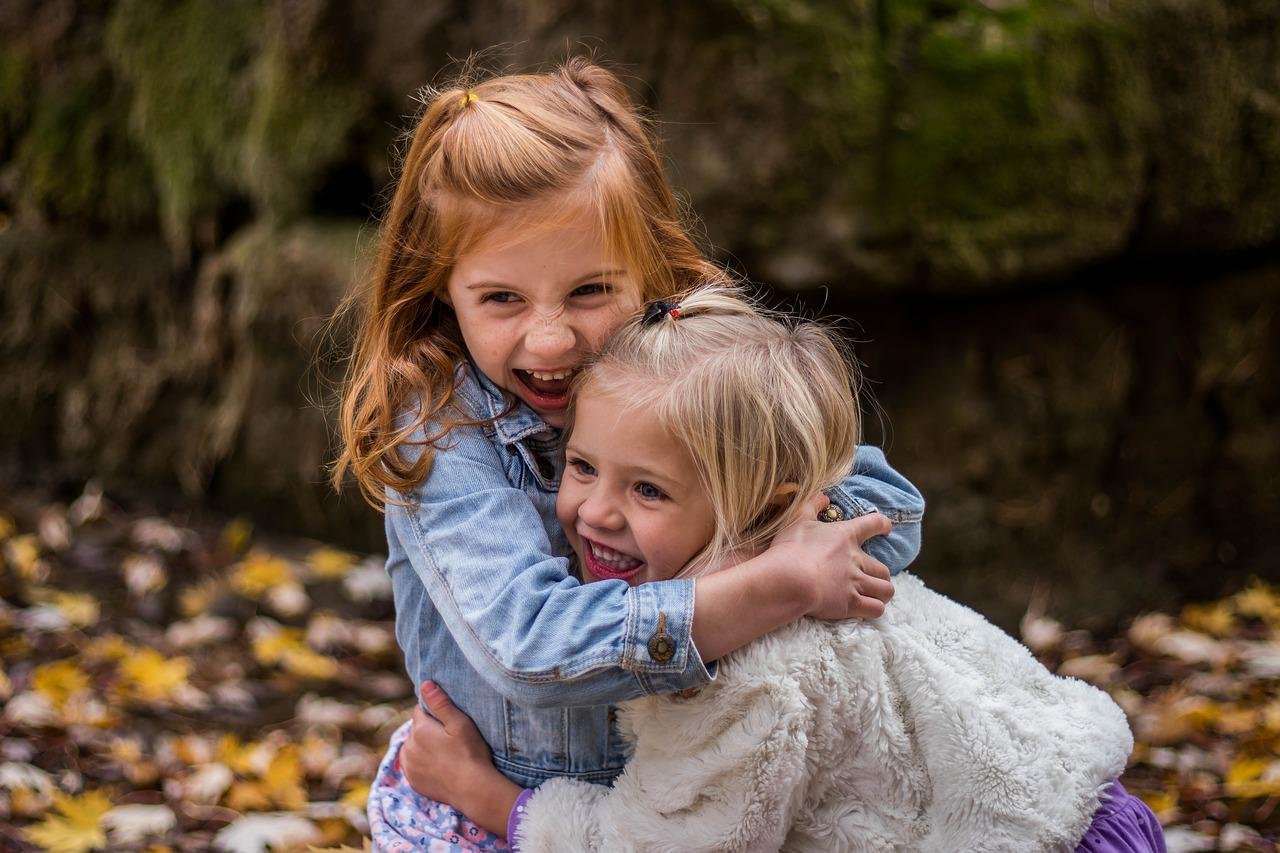 Duas meninas brancas se abraçando e sorrindo