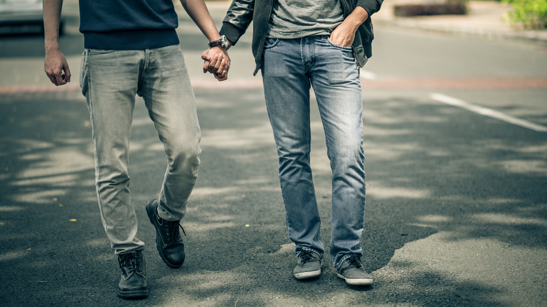 Casal homoafetivo andando de mãos dadas pela rua