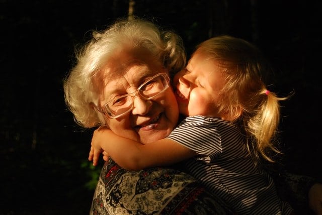 Menina abraçando avó e sorrindo
