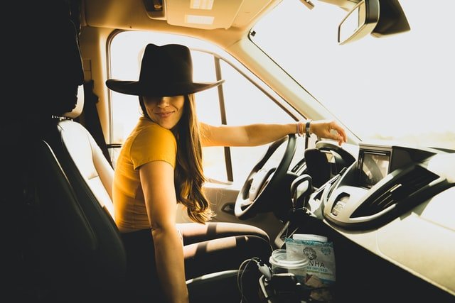Mulher de chapéu dirigindo carro