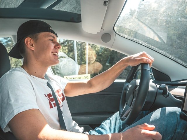 Menino jovem sorrindo enquanto dirige