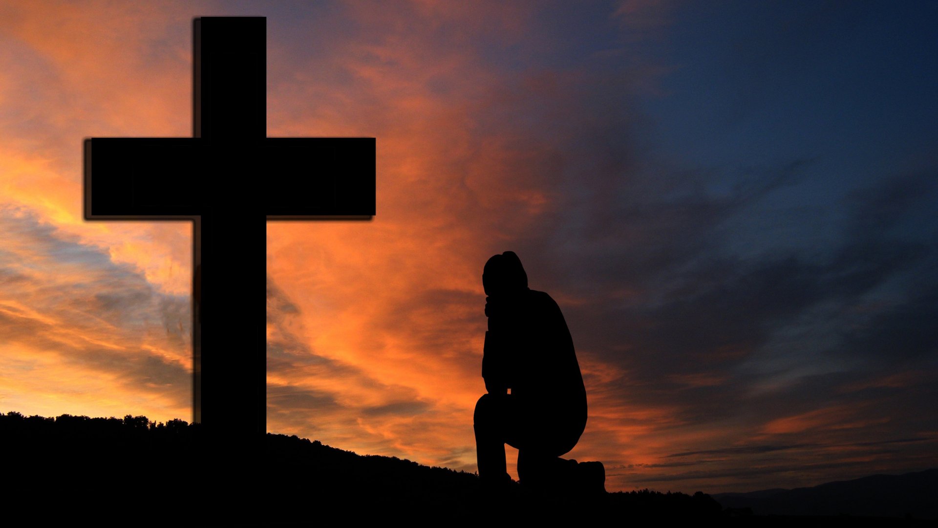 Silhueta de homem rezando nos pés da cruz sob o por do sol
