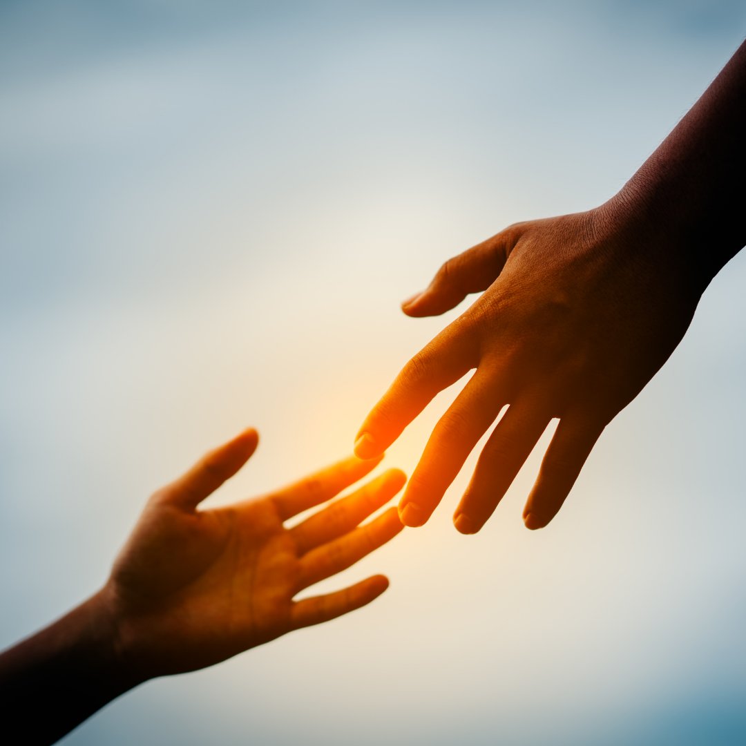 Mão estendida para outra pessoa durante o nascer do sol