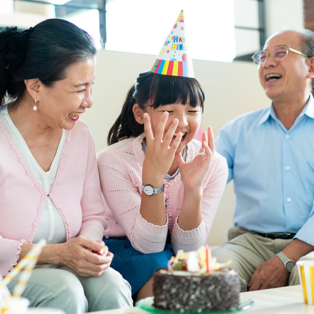 Adolescente asiática sorrindo usando chapéu de aniversário e avós ao lado