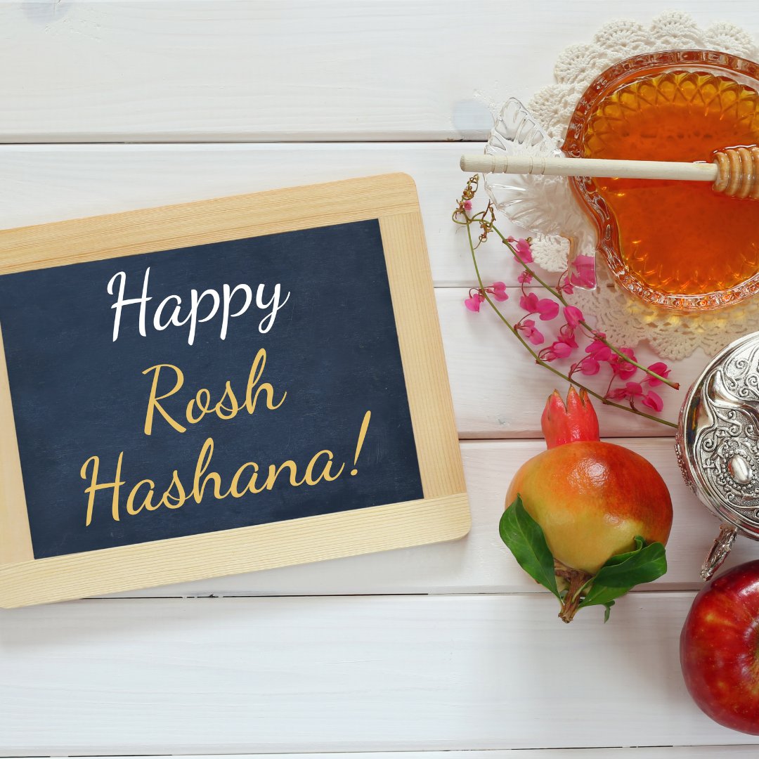 Lousa com dizeres Feliz Rosh Hashana, romã e mel ao lado