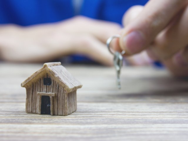Pequena casa e pessoa segurando chave