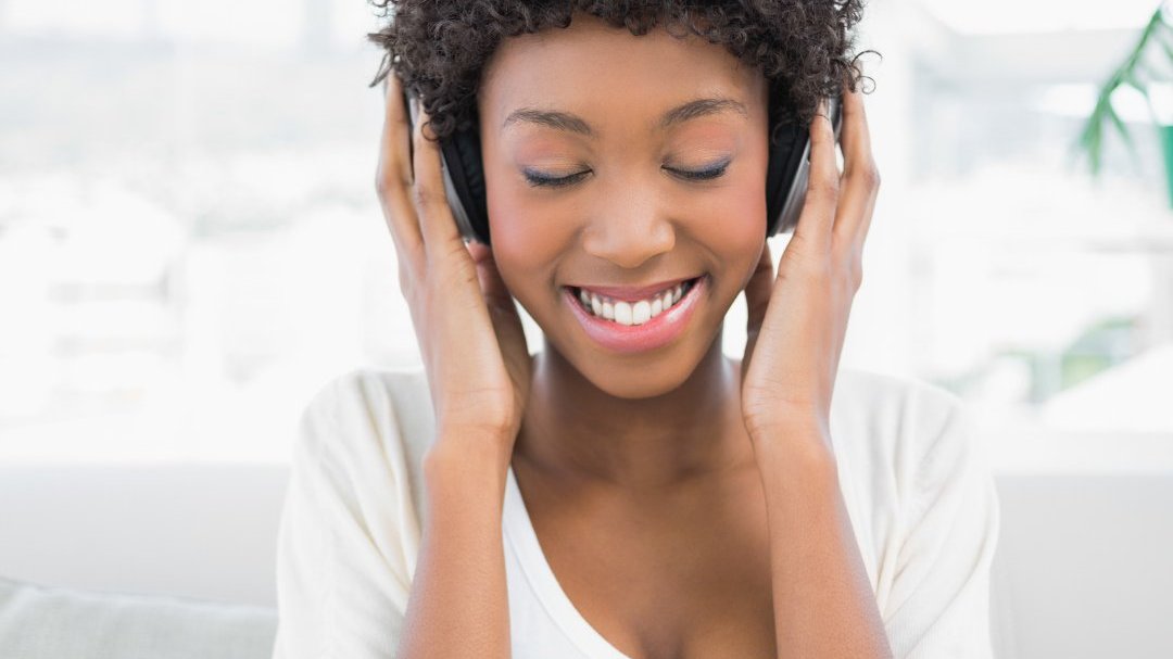 Mulher sorrindo e escutando música com fone de ouvido