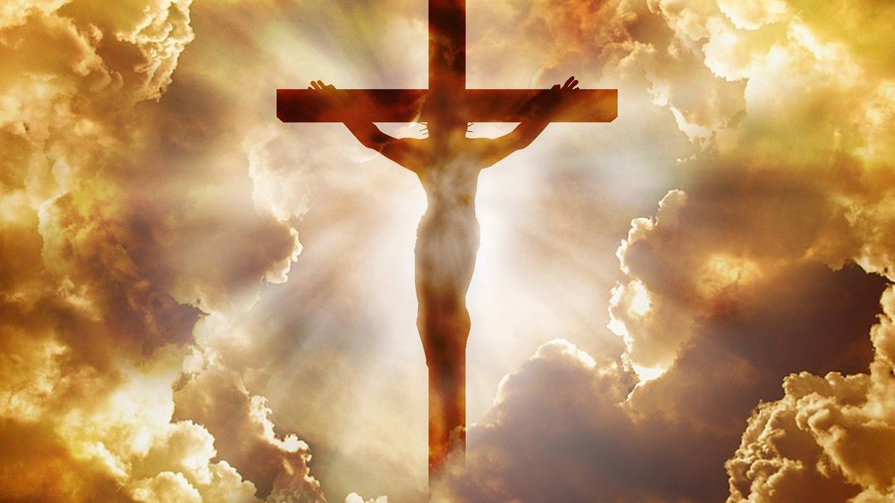Jesus Cristo sendo crucificado na Cruz, Ao fundo, um brilho intenso foca em sua imagem, enquanto as nuvens entornam a Cruz e Jesus Cristo