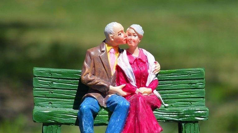 Dois bonecos de avós sentados num banco também de brinquedo