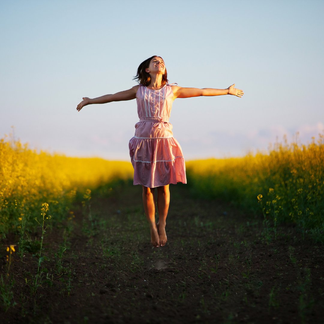 Kapulya / Getty Images Pro / Canva Mulher em um campo com os braços abertos, olhando para o céu