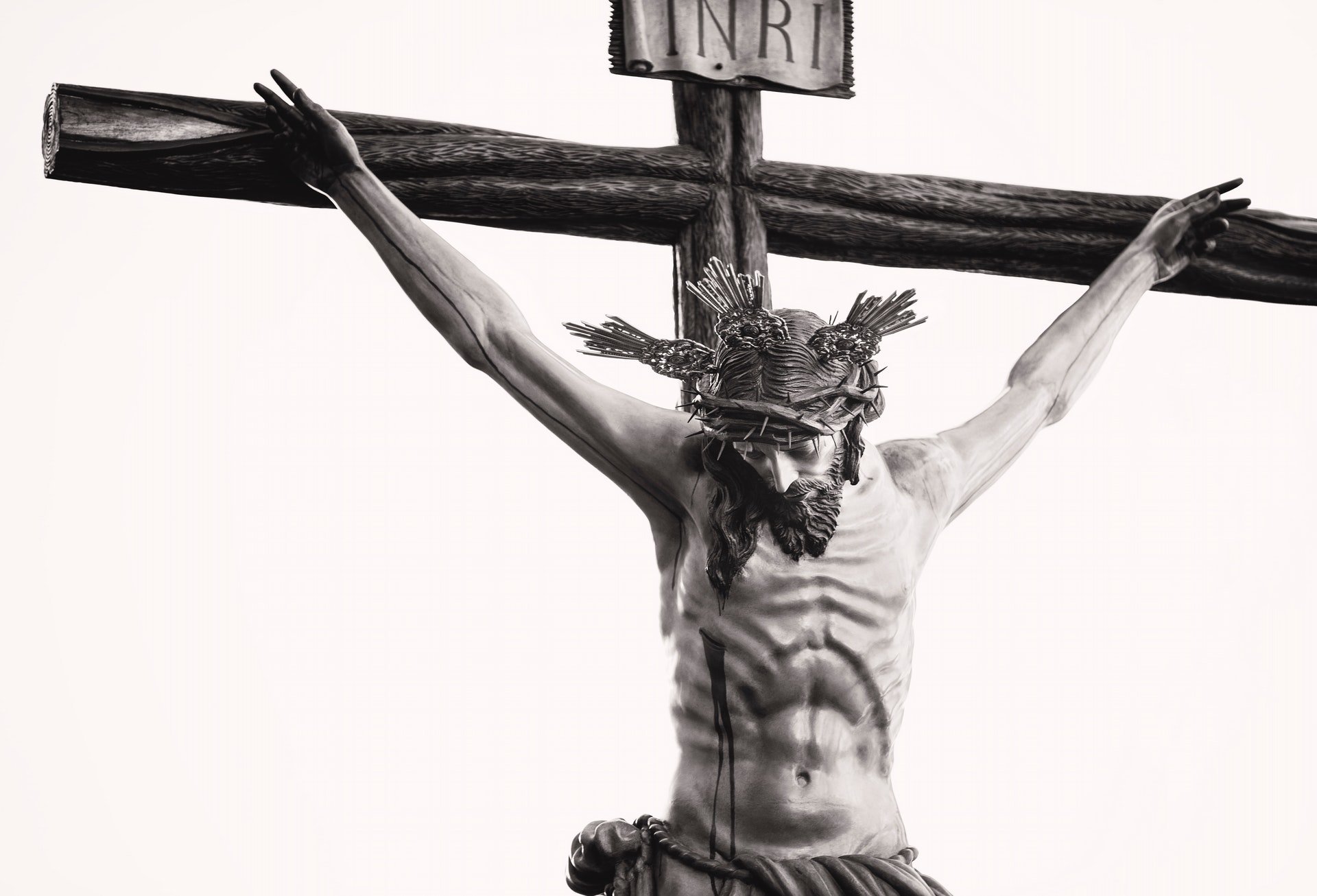 Uma arte plástica de um crucifixo com Jesus Cristo. No topo da cruz, uma placa escrita com 'inri'