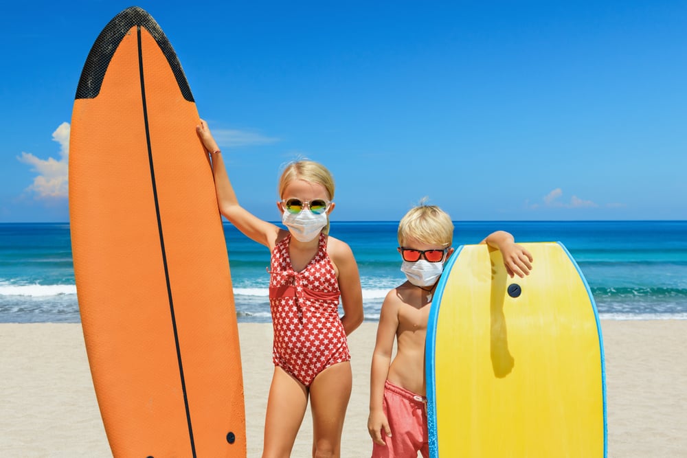 Crianças surfistas de máscara na praia