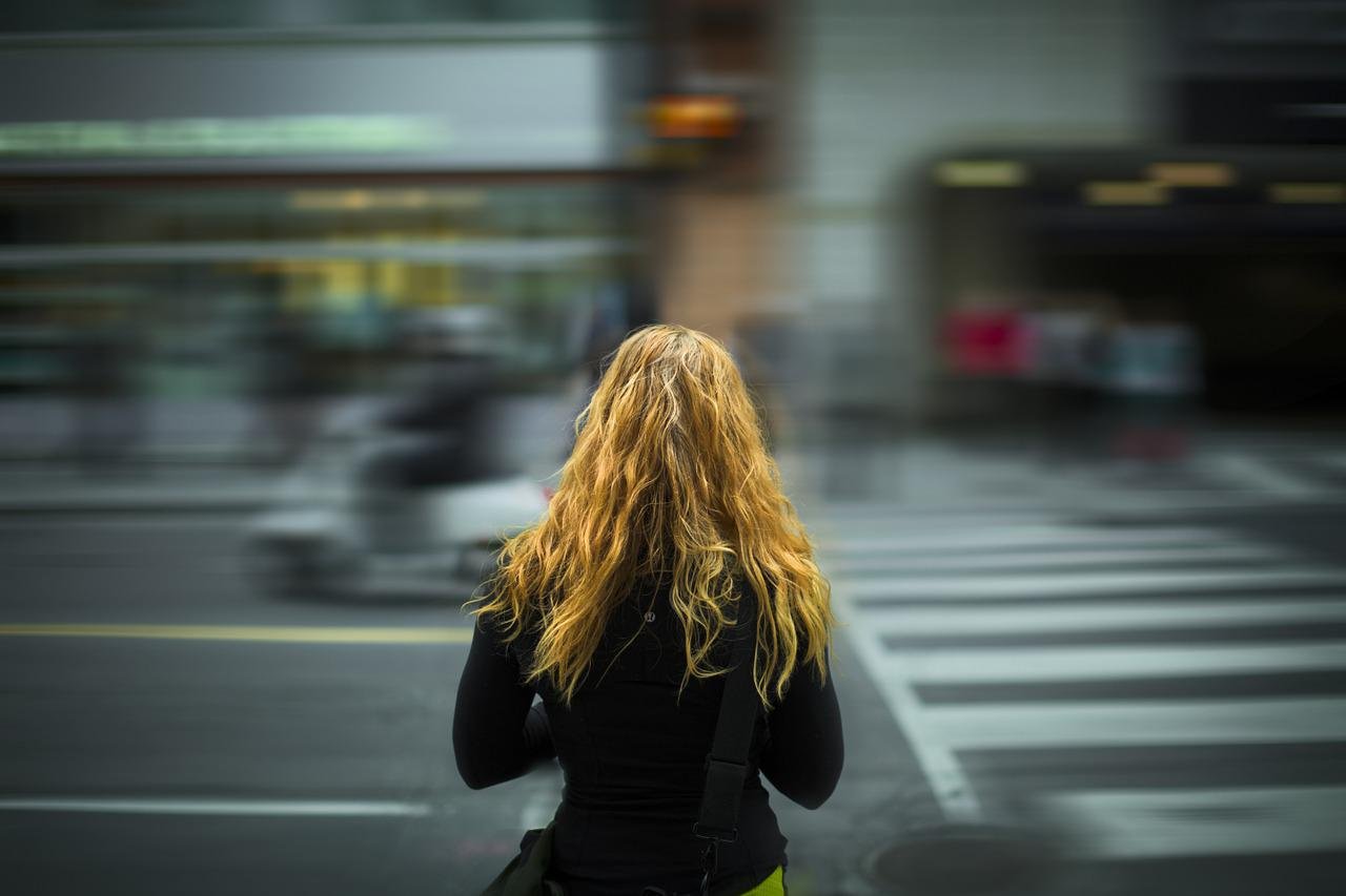 Garota loira de cabelos longos de costas no meio da rua