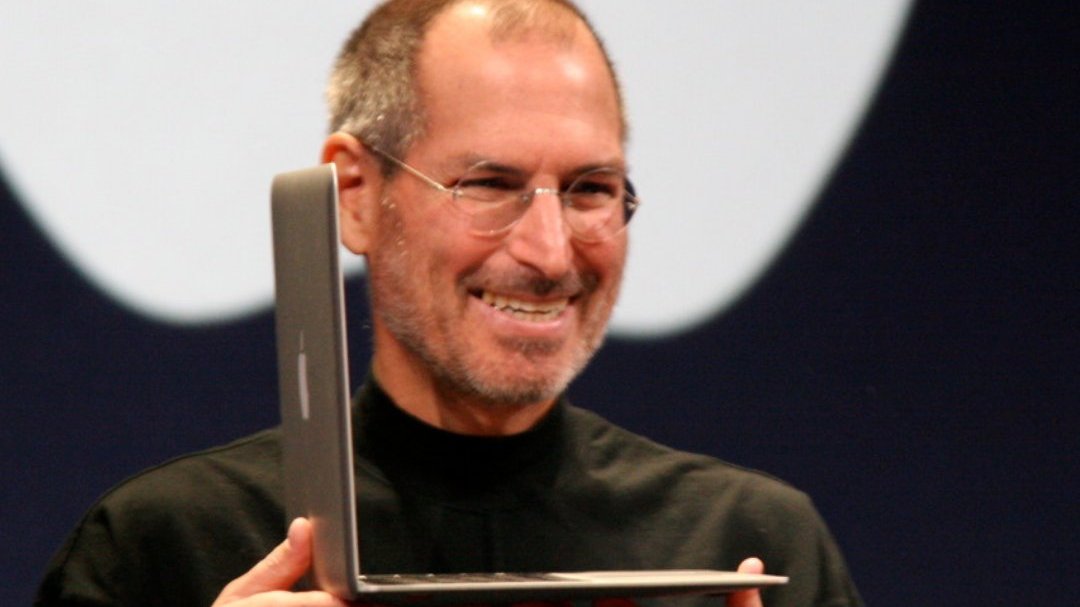 Imagem do empresário americano Steve Jobs segurando um notebook