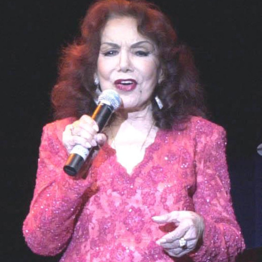 Imagem da cantora Emilinha Borba cantando durante show