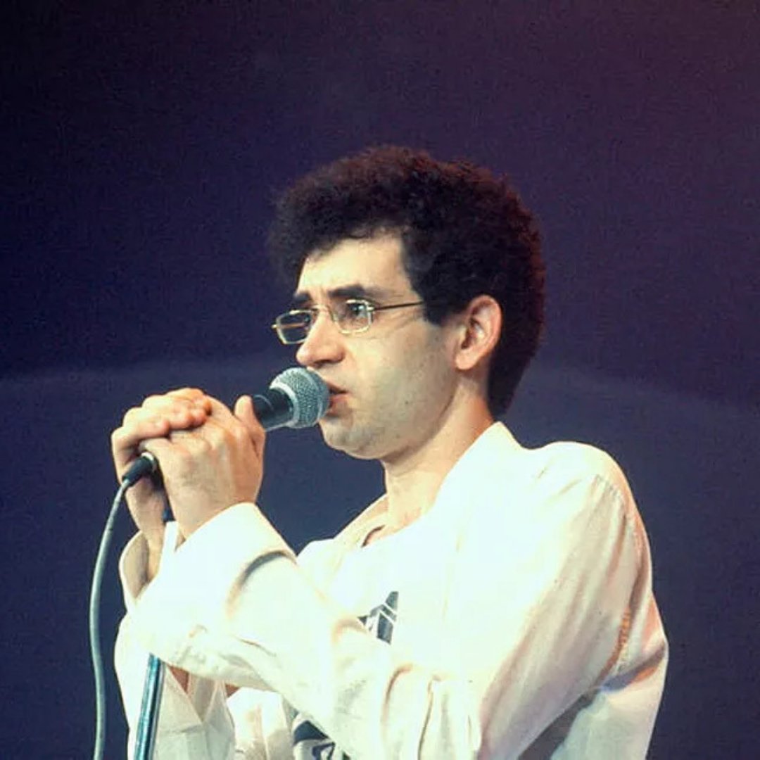 Imagem do cantor Renato Russo segurando um microfone e cantando