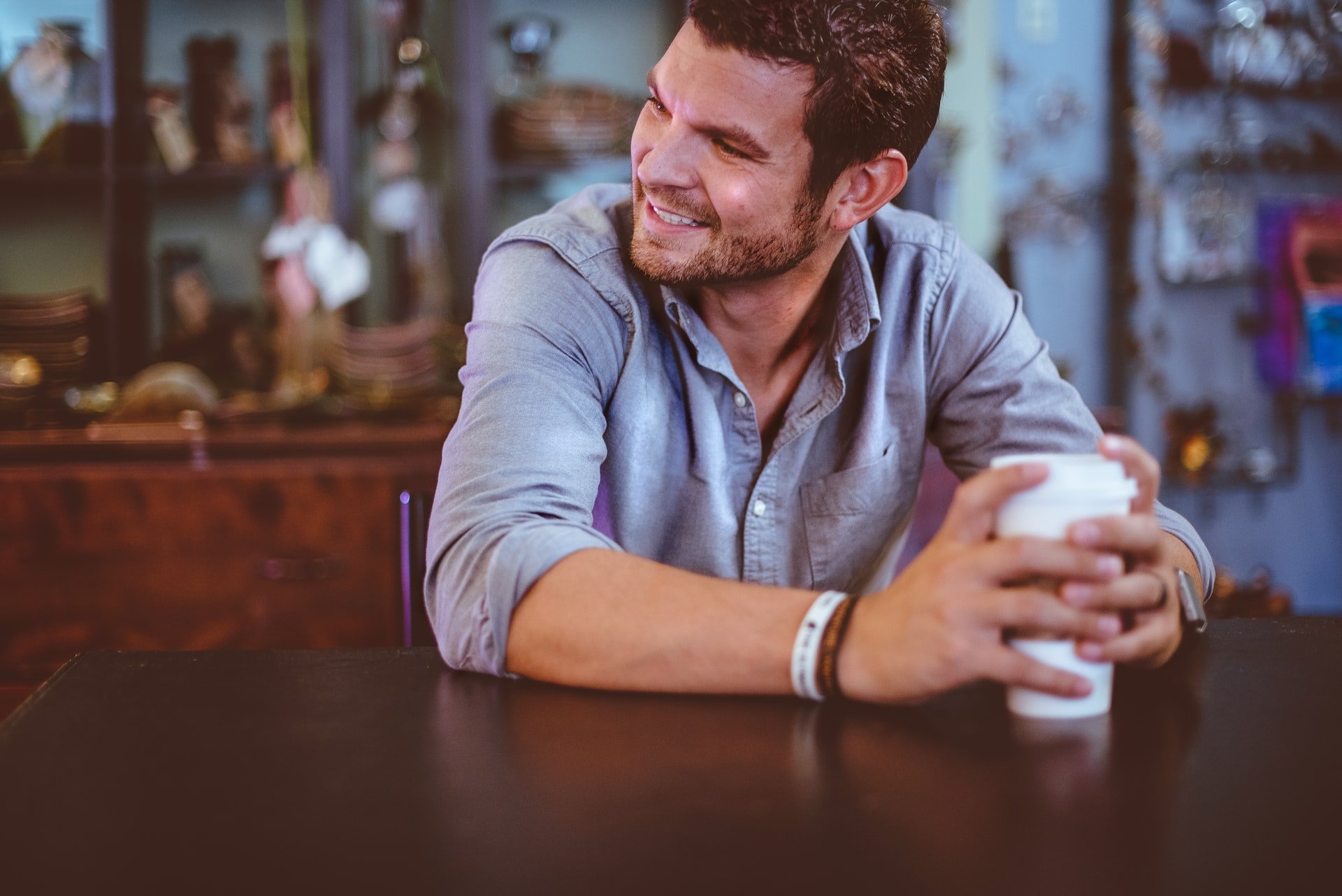 Homem branco sorrindo segurando copo de café.