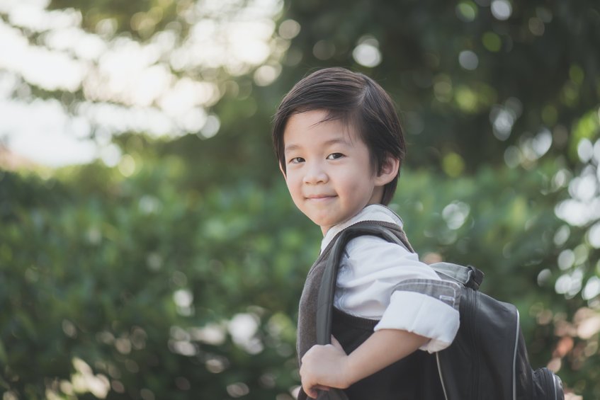 Criança de uniforme e mochila sorrindo