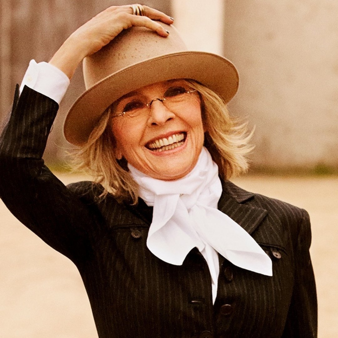 Imagem da atriz norte americana Diane Keaton, sorrindo e segurando o chapéu