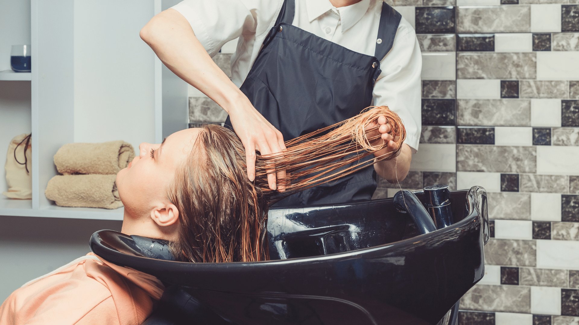Pessoa lavando o cabelo de uma mulher em um lavatório