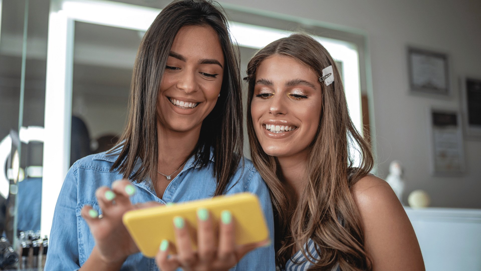 Duas mulheres sorrindo enquanto olham o celular