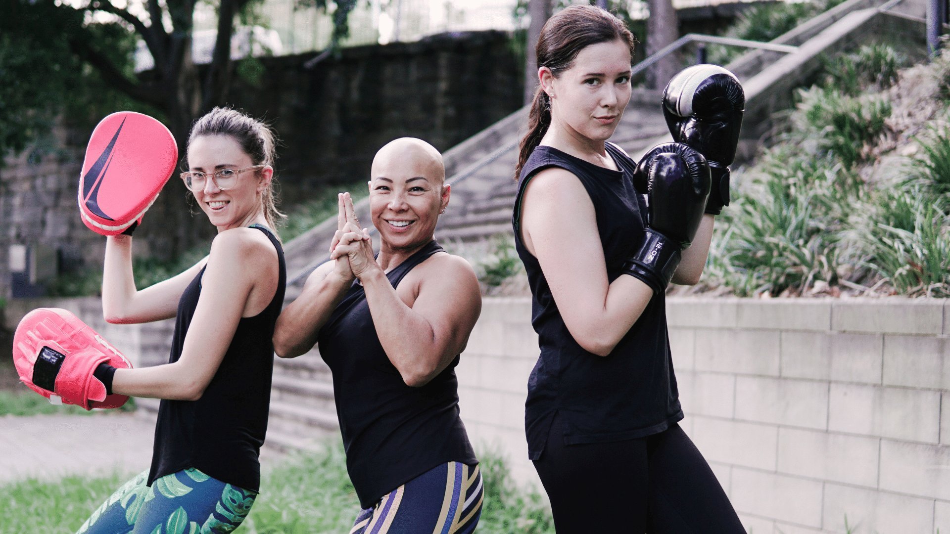 3 mulheres sorrindo e se mantendo em poses de luta