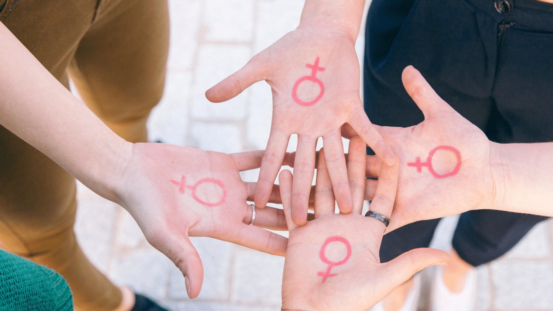 Quatro mãos voltadas para cima com o símbolo do feminismo desenhado nas palmas