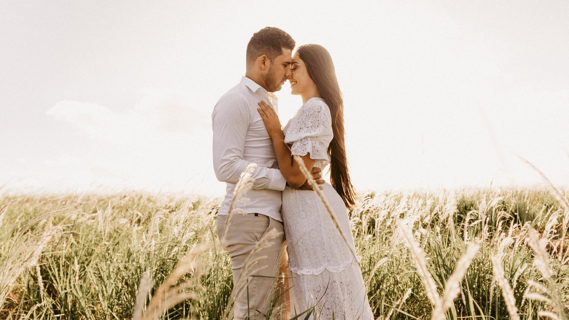 Casal abraçado olhando um para o outro em meio a um campo