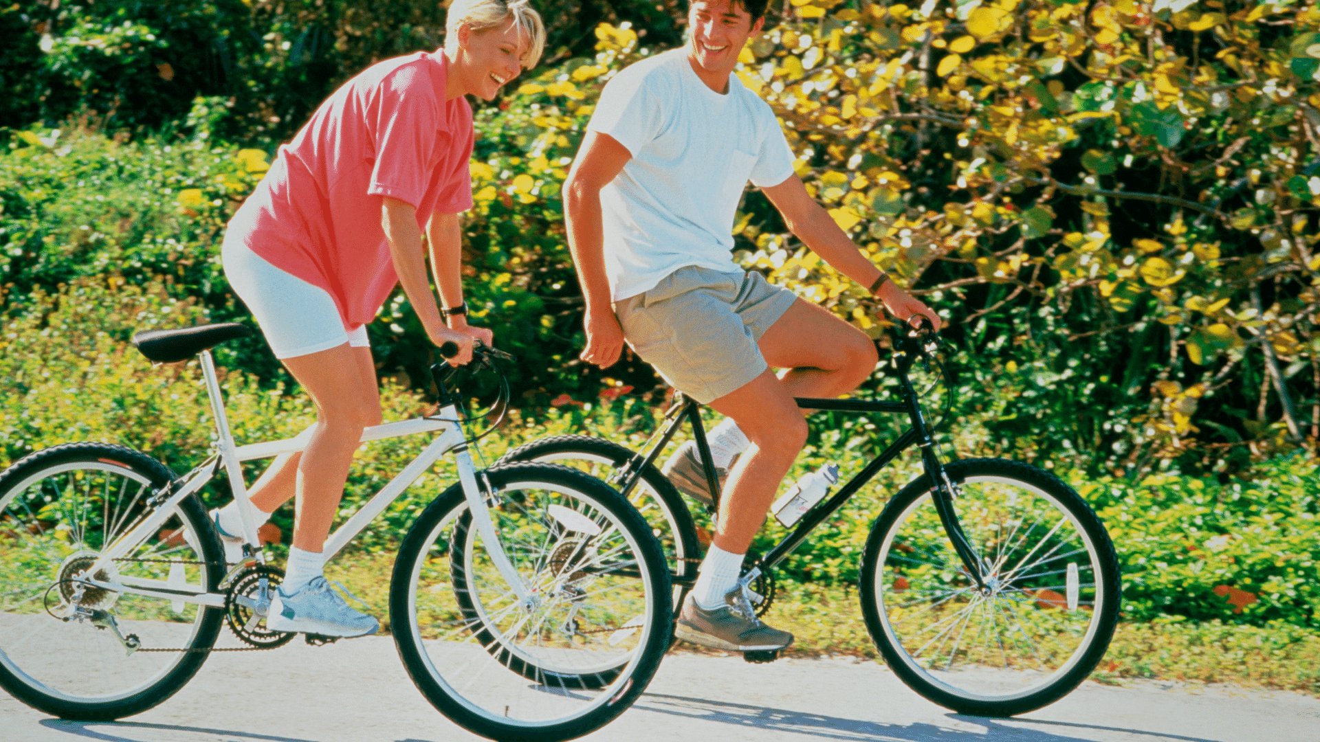 Mulher e homem dando risada ao andar de bicicleta