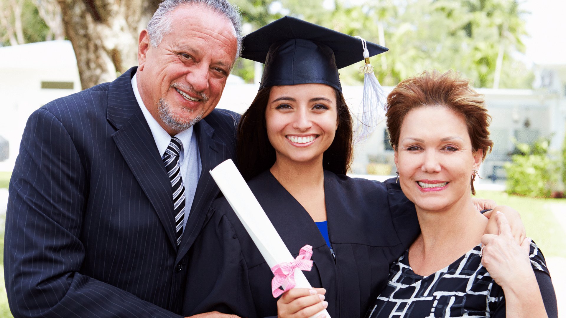 Filha segurando seu diploma abraçada com seu pai e mãe, todos felizes comemorando sua graduação