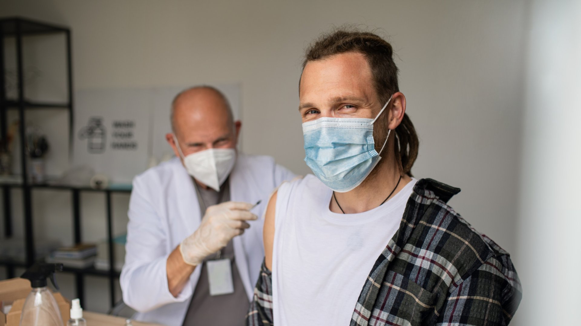 Homem de máscara tendo a vacina aplicada em seu braço por outro homem também de máscara