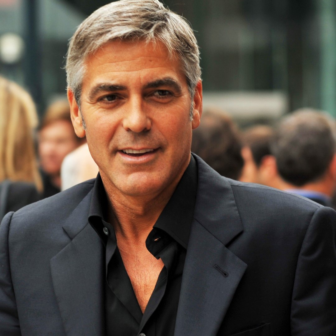 George Clooney no meio de uma multidão vestindo roupa social