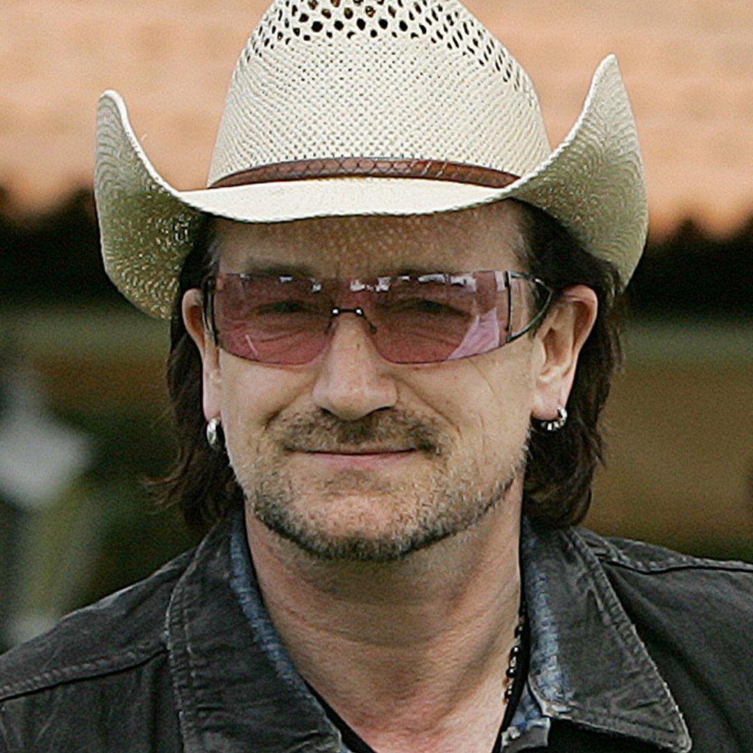 Imagem do vocalista da banda U2, Bono Vox, usando um chapéu e óculos com lentes avermelhadas