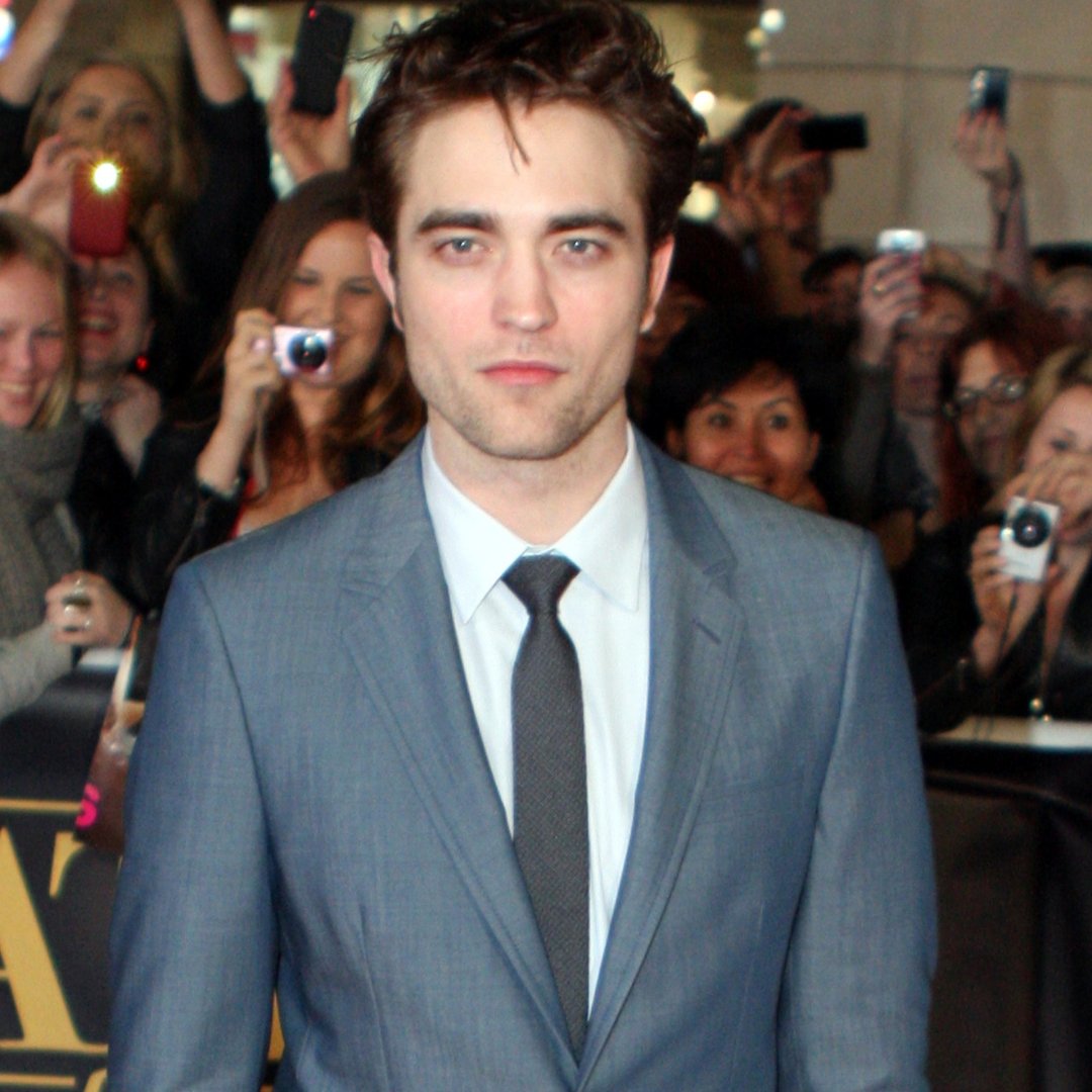 Ator Robert Pattinson de paletó sendo fotografado em um evento