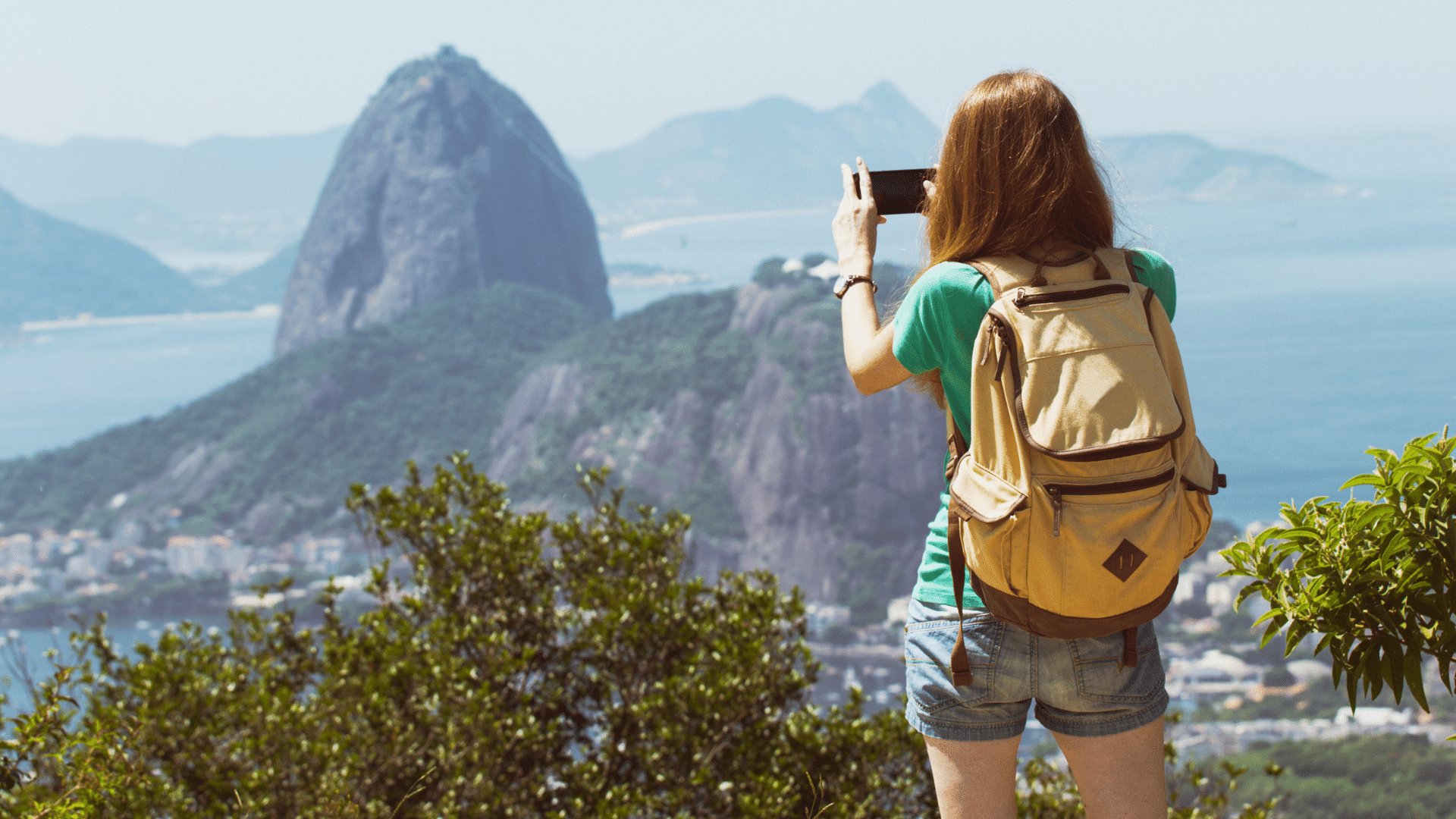 Mulher em pé tirando uma foto do Rio de Janeiro