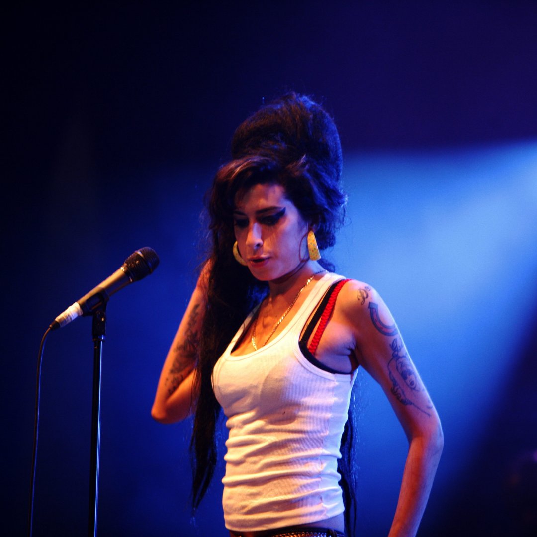 Imagem da cantora Amy Winehouse cantando em um show
