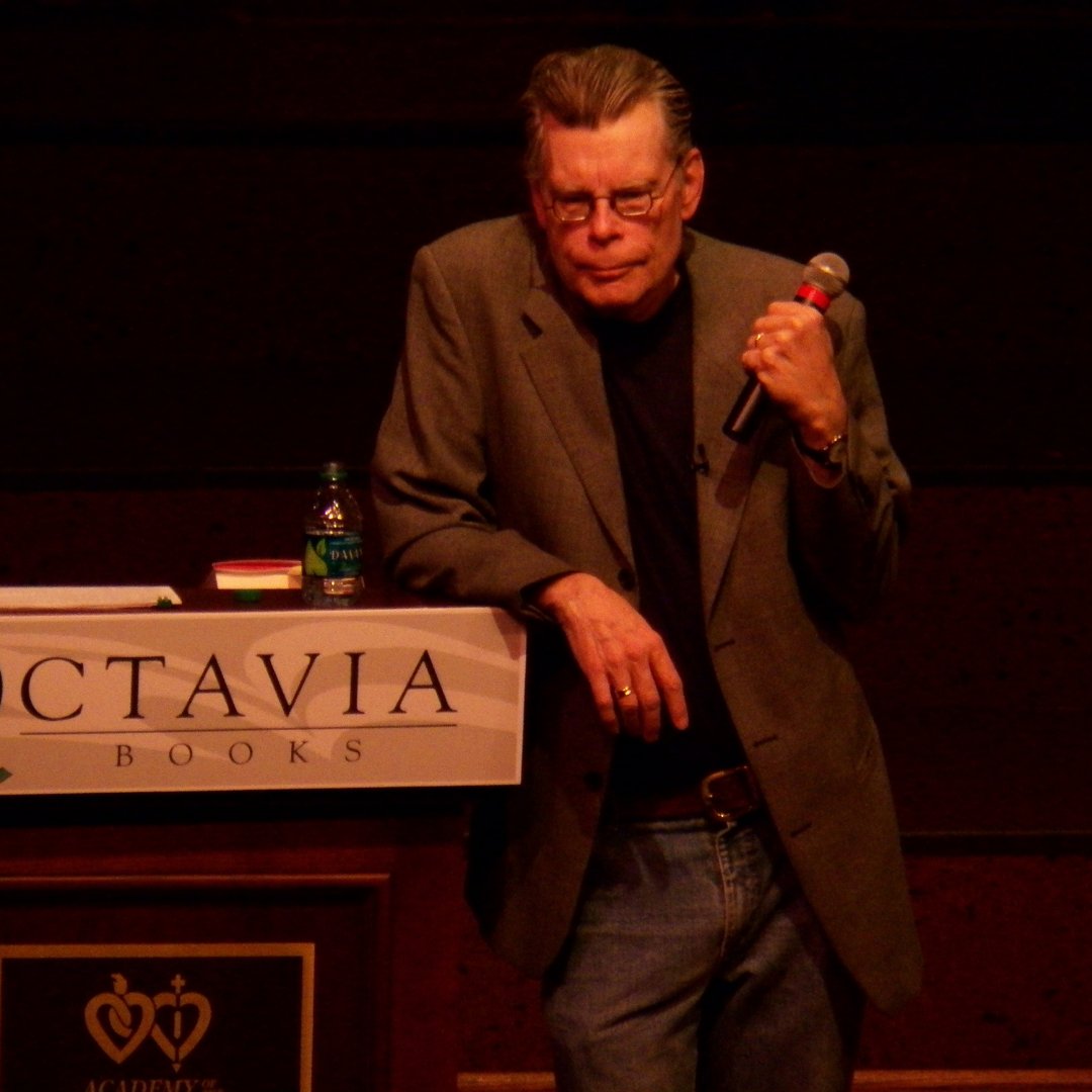 Imagem do escritor Stephen King com um microfone na mão em um evento