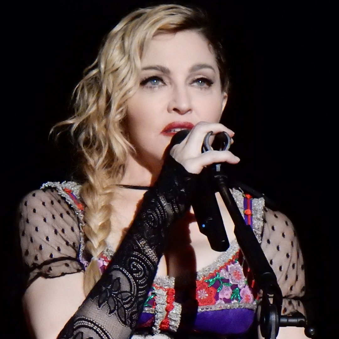 Imagem da cantora e dançarina Madonna falando no microfone