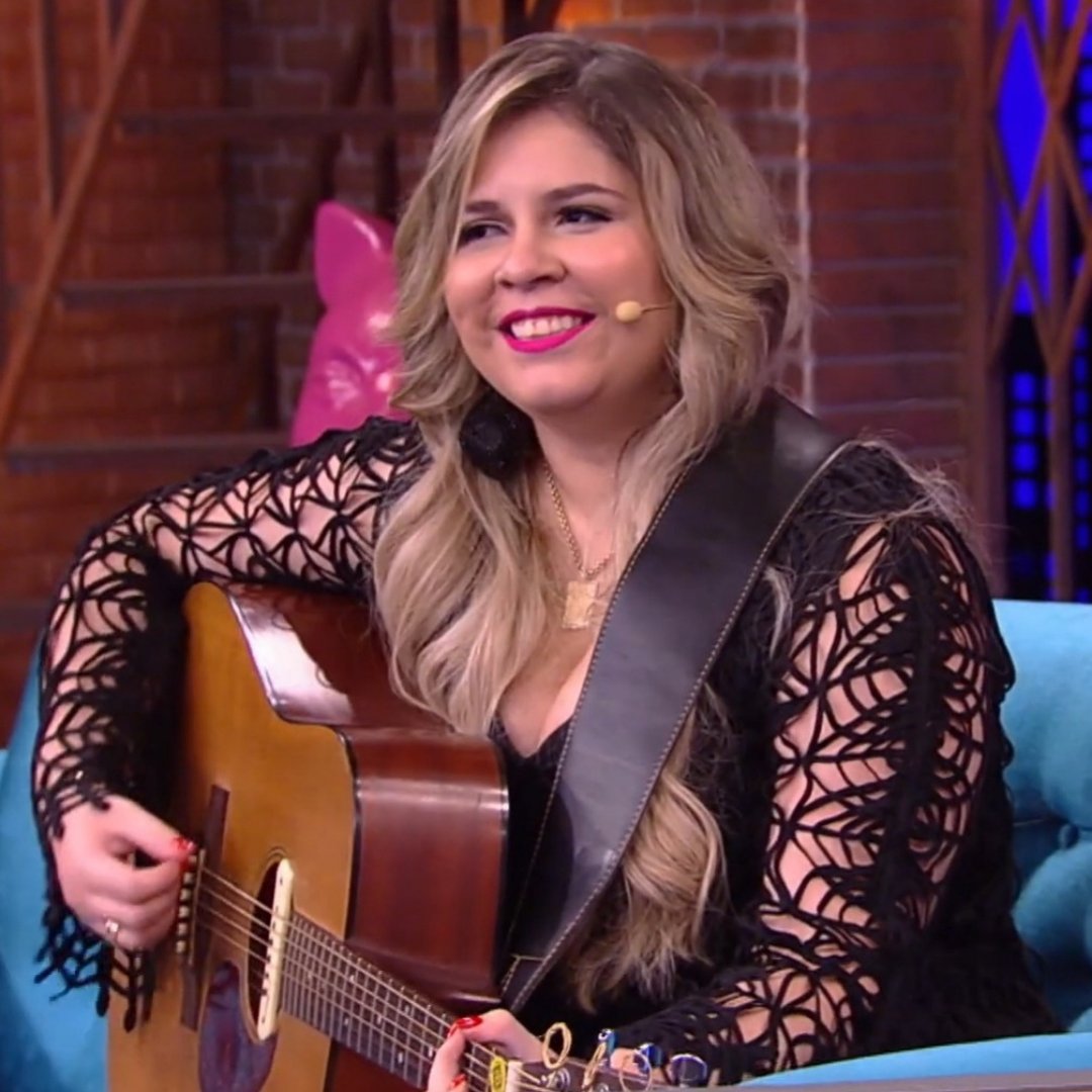 Imagem da cantora Marília Mendonça tocando violão durante programa de tv