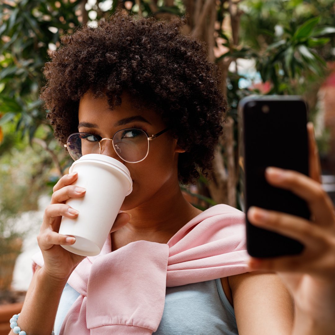 Mulher tirando uma selfie tomando café