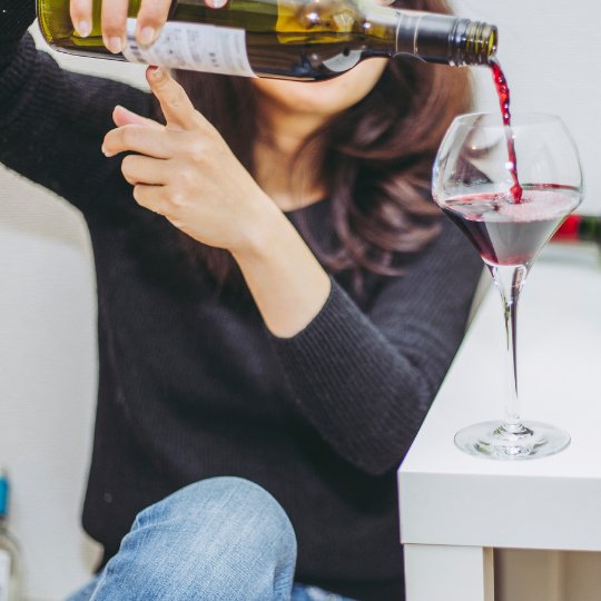 Uma mulher inserindo vinho numa taça.