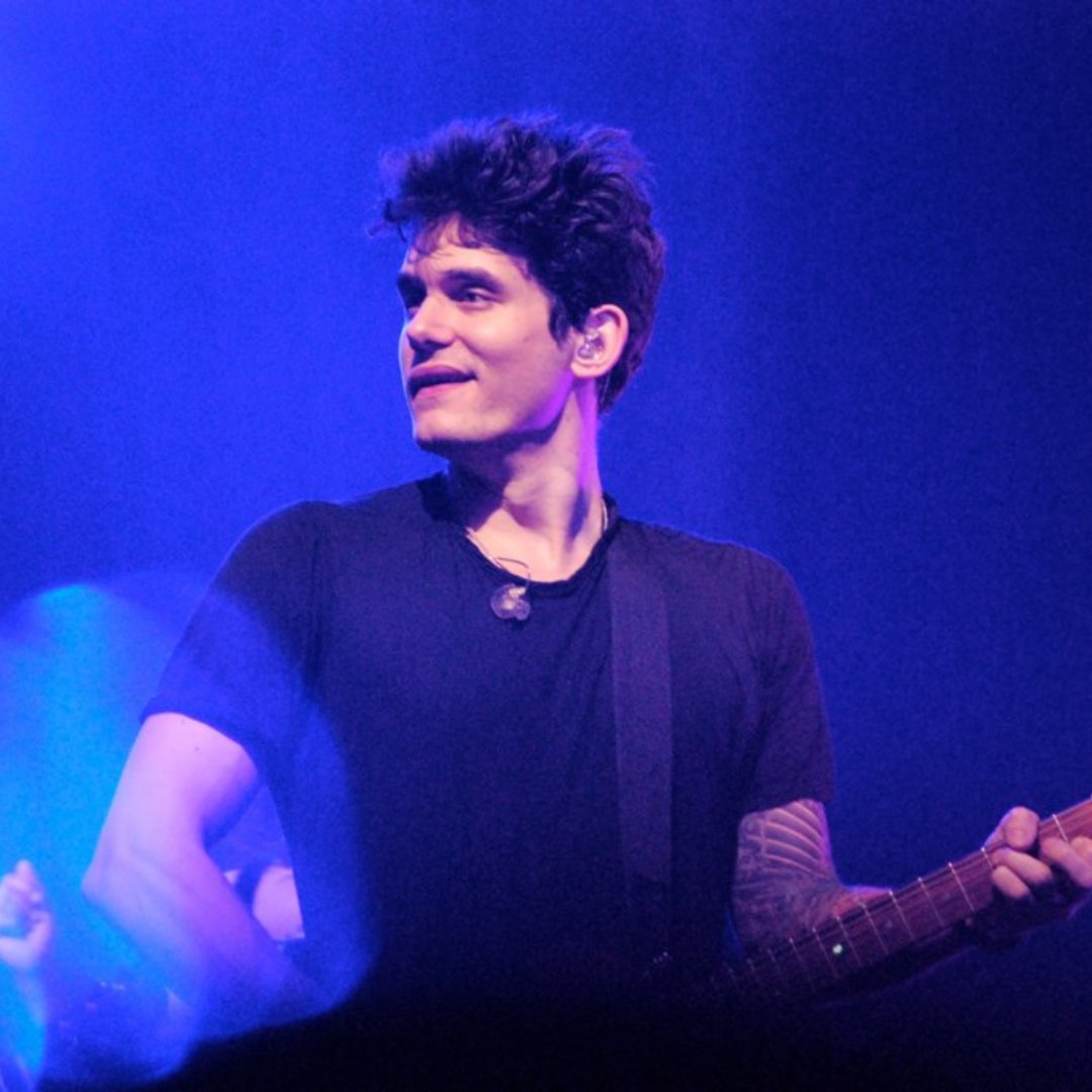 Imagem do cantor John Mayer tocando guitarra em um show