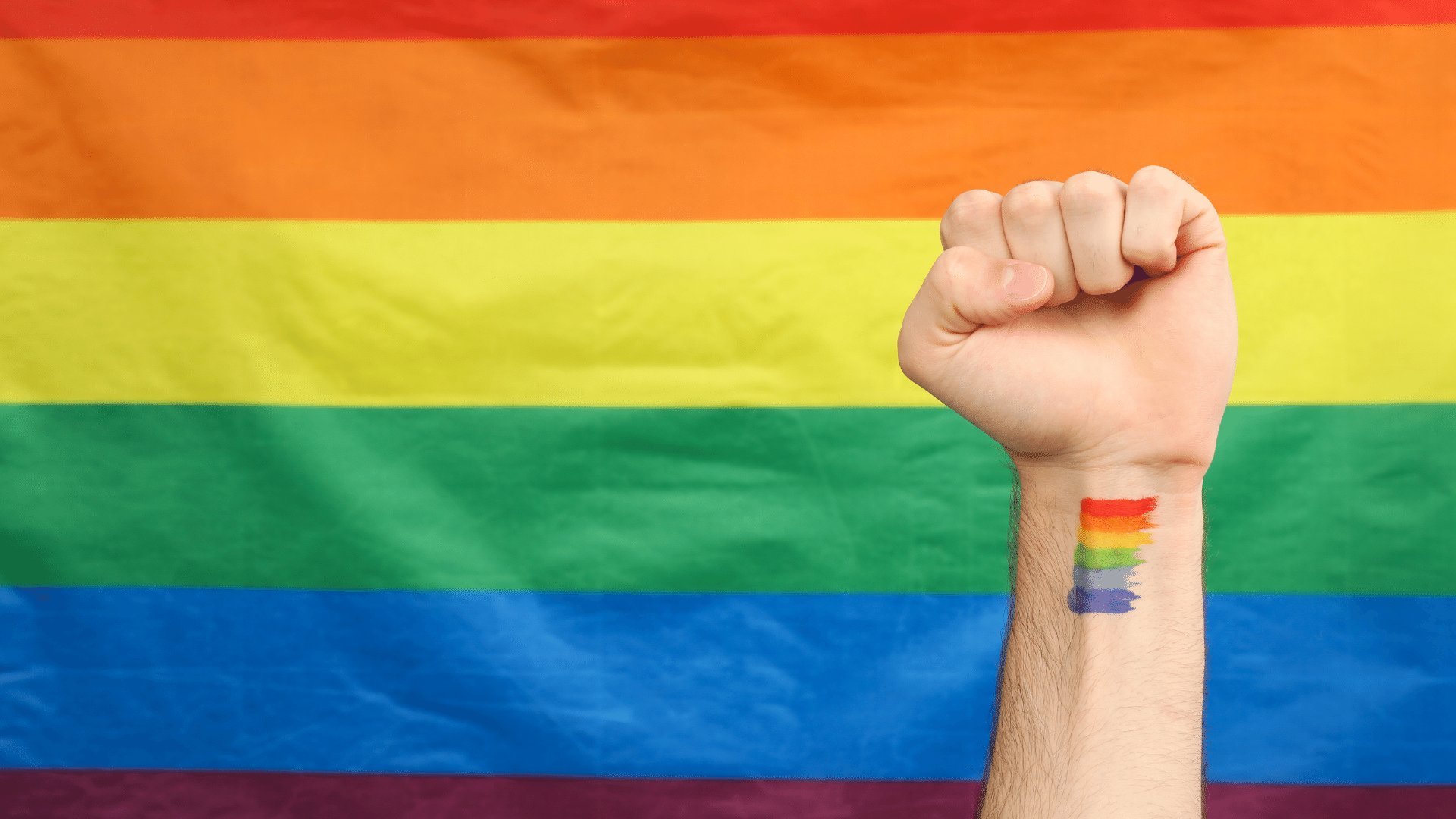 atlasstudio / Canva Pro Punho cerrado e bandeira LGBTQIA+