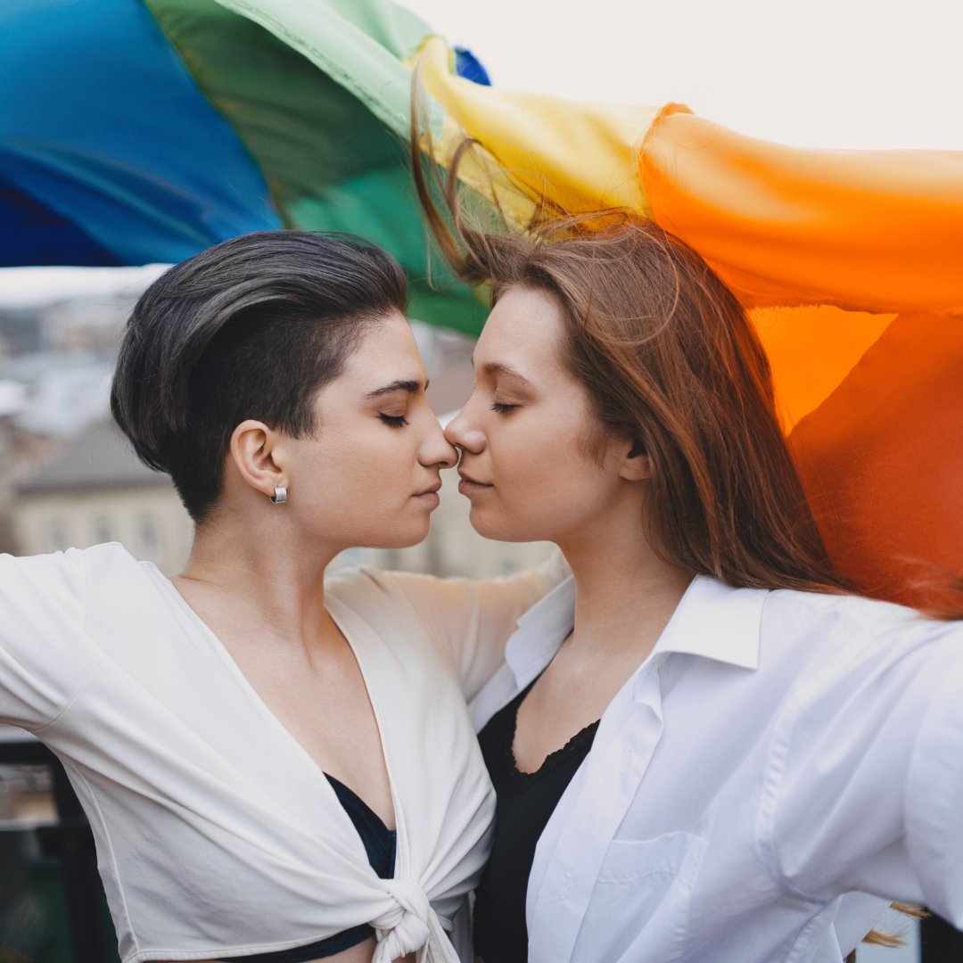 Duas mulheres se beijando e segurando a bandeira lgbt
