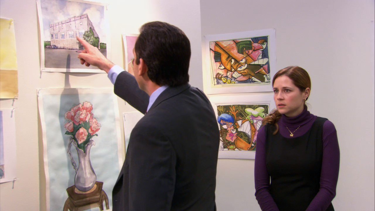 Pam e Michael em uma sala de exposição com folhas de desenhos nas paredes. Michael aponta para um desenho e Pam o observa.