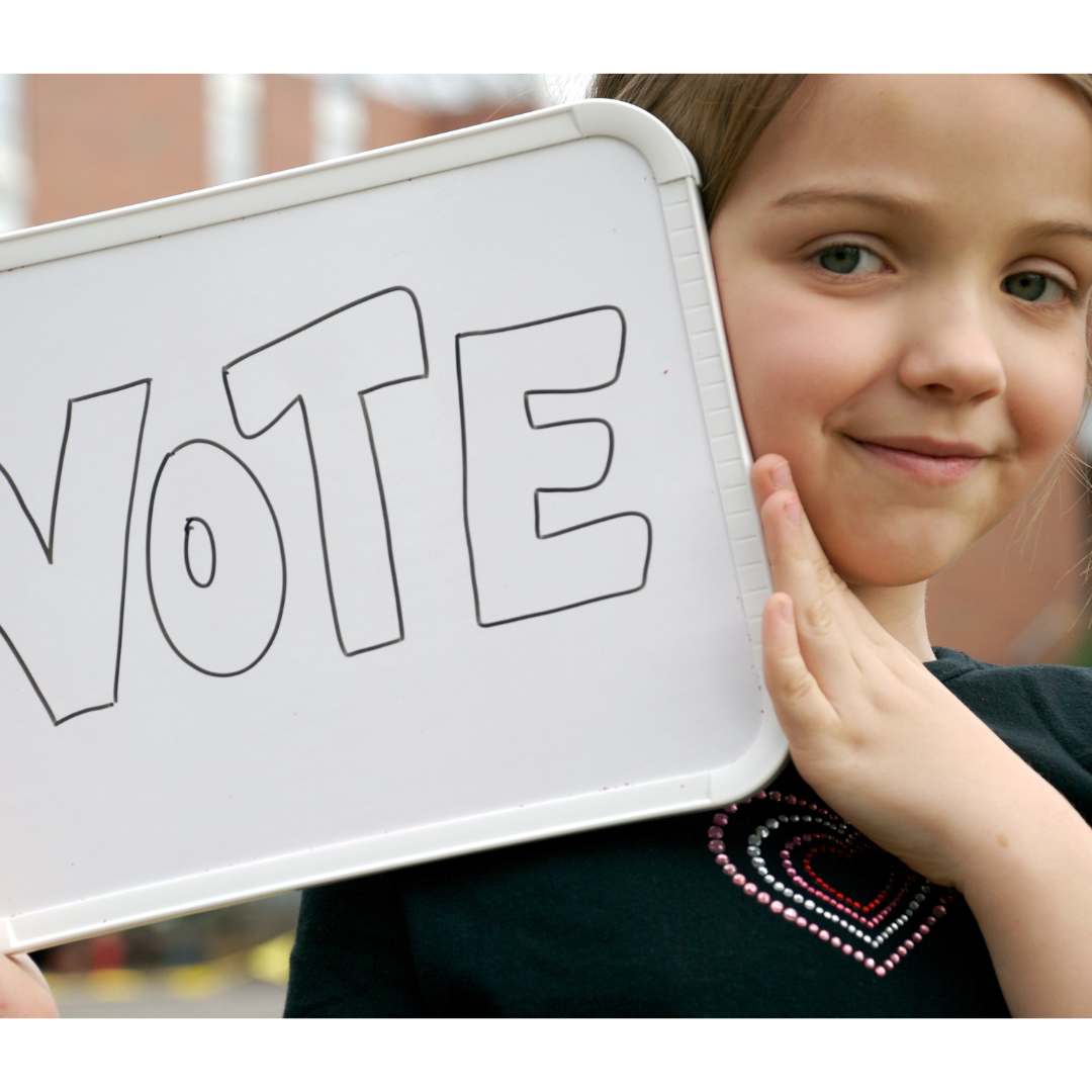 Criança segurando uma placa escrito Vote