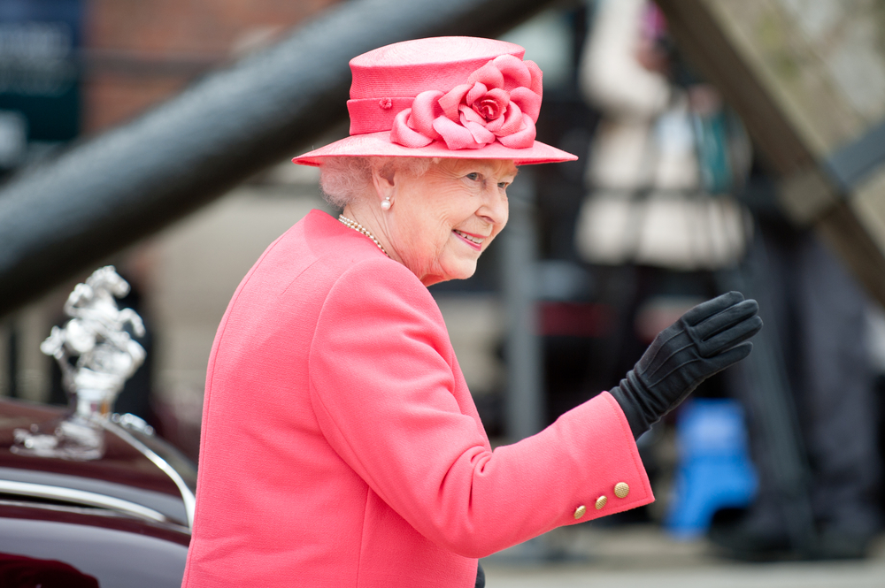 Rainha Elizabeth II com roupas rosas e luva preta.
